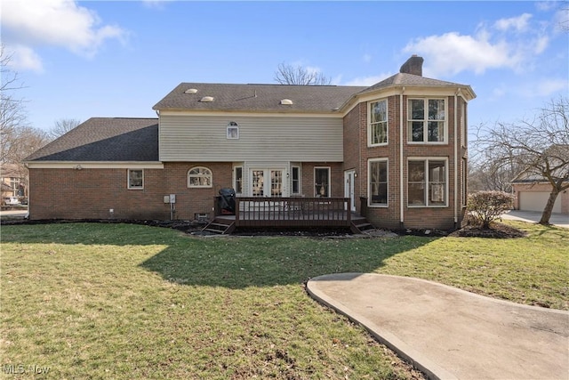 back of property featuring brick siding, a lawn, a deck, and a chimney