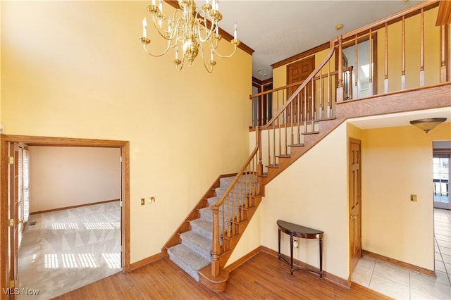 stairs featuring baseboards, wood finished floors, and a towering ceiling