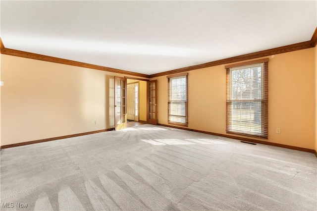 empty room featuring visible vents, baseboards, light colored carpet, and ornamental molding