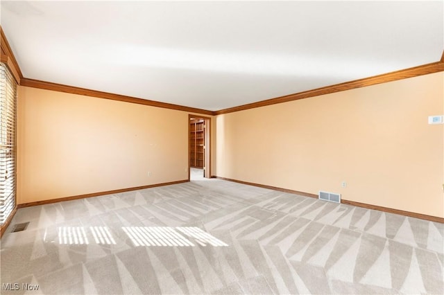 empty room featuring crown molding, light colored carpet, and visible vents