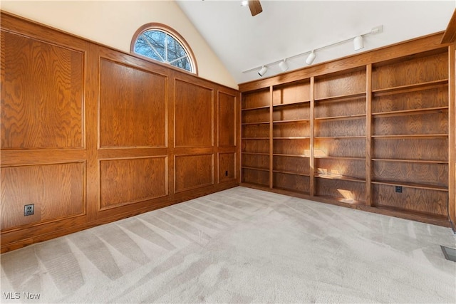 empty room featuring built in shelves, a ceiling fan, lofted ceiling, track lighting, and light colored carpet