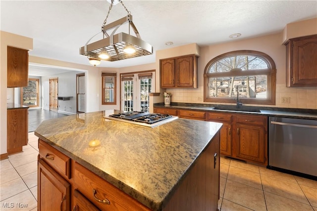 kitchen featuring light tile patterned floors, gas stovetop, stainless steel dishwasher, tasteful backsplash, and a center island