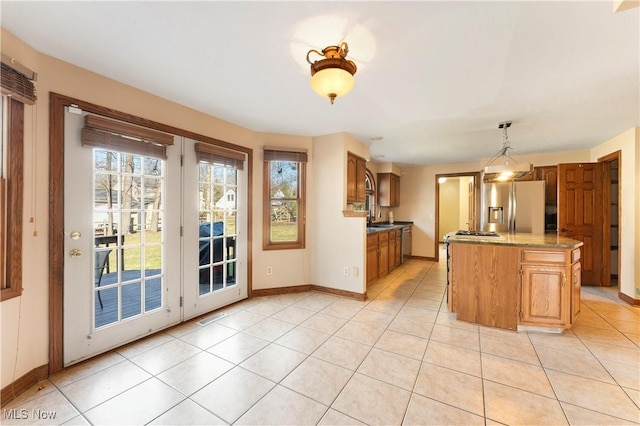 kitchen with light tile patterned floors, visible vents, stainless steel appliances, decorative light fixtures, and a center island