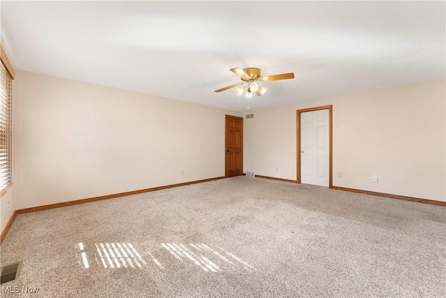 empty room featuring visible vents, light colored carpet, baseboards, and ceiling fan