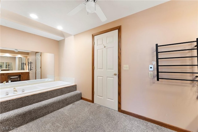 bathroom with a washtub, carpet flooring, baseboards, ceiling fan, and vanity