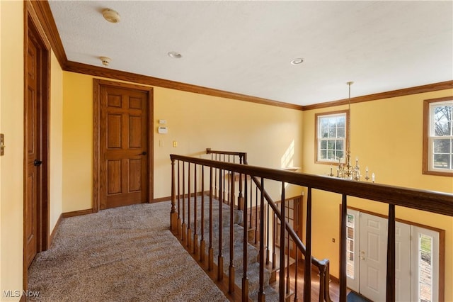 hallway featuring carpet, an upstairs landing, baseboards, and ornamental molding