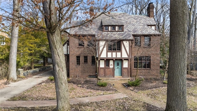 tudor-style house featuring stucco siding, a high end roof, brick siding, and a chimney