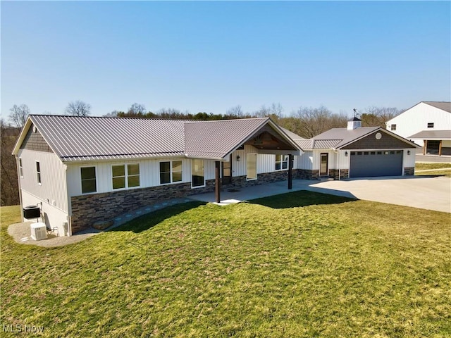 ranch-style home with a standing seam roof, stone siding, concrete driveway, a front yard, and metal roof