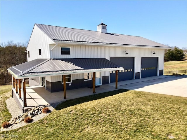 exterior space featuring a yard, a chimney, concrete driveway, a garage, and metal roof