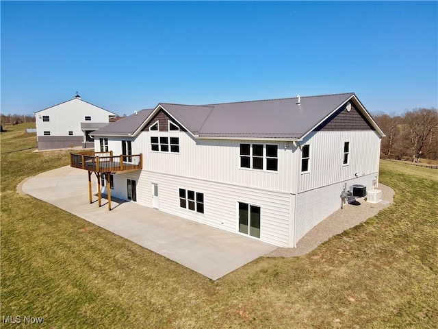 back of property featuring a patio area, a lawn, metal roof, and a deck