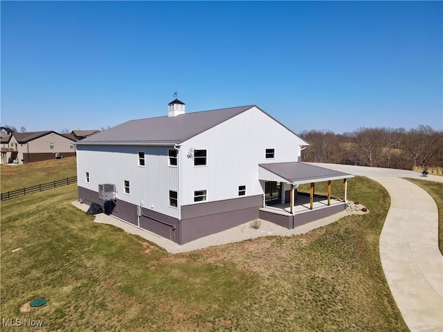 view of property exterior with a lawn, central AC, and fence