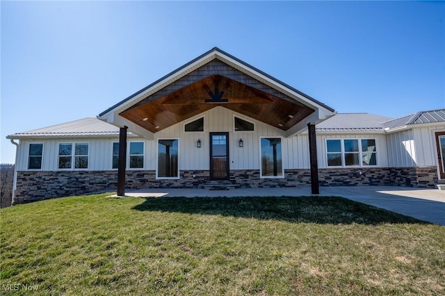 modern inspired farmhouse with a front lawn, board and batten siding, stone siding, and metal roof