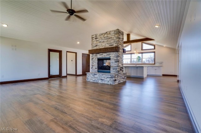 unfurnished living room with baseboards, lofted ceiling, dark wood-style flooring, ceiling fan, and a stone fireplace