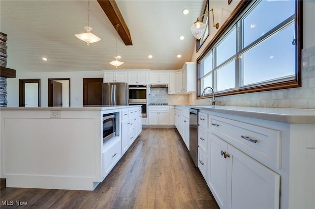 kitchen featuring backsplash, light countertops, beam ceiling, stainless steel appliances, and a sink