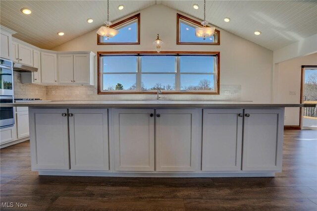 kitchen featuring backsplash, vaulted ceiling, and white cabinetry