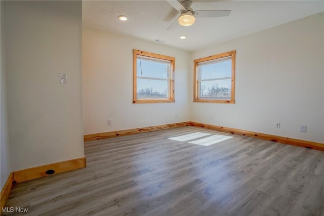 spare room featuring visible vents, ceiling fan, baseboards, and wood finished floors