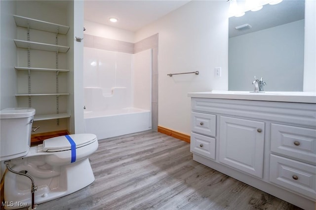 bathroom featuring baseboards, toilet, wood finished floors, and vanity