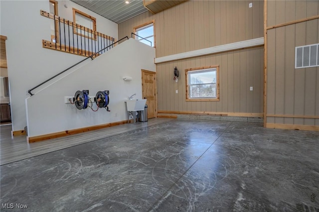 unfurnished living room featuring a high ceiling, concrete flooring, visible vents, and a wealth of natural light