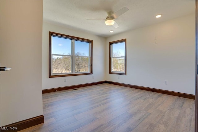 empty room with visible vents, ceiling fan, baseboards, and wood finished floors