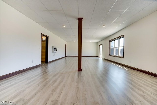 spare room with light wood finished floors, recessed lighting, a paneled ceiling, and baseboards