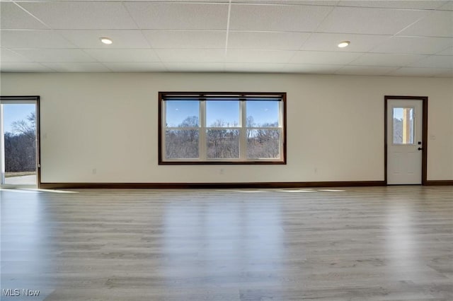 spare room with a paneled ceiling, baseboards, and wood finished floors