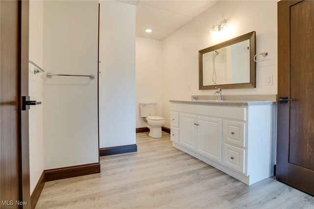 bathroom with baseboards, toilet, wood finished floors, and vanity