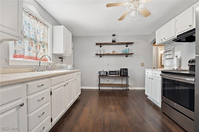 kitchen with dark wood finished floors, light countertops, stainless steel range with electric stovetop, white cabinetry, and a sink