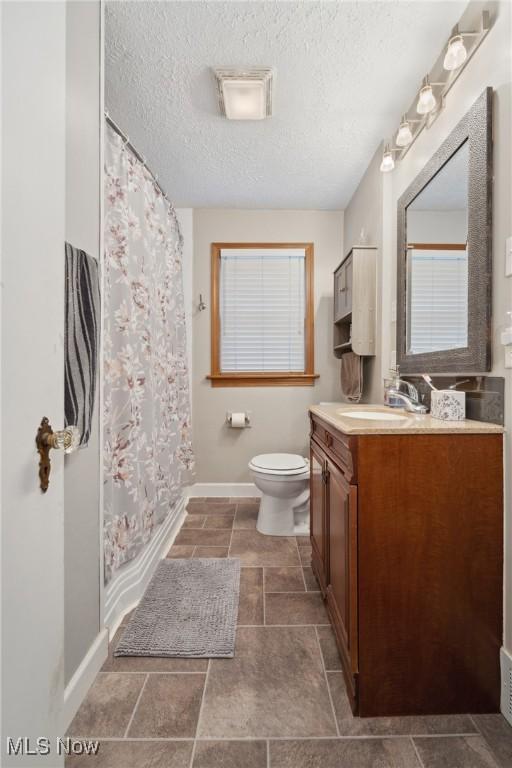 bathroom with vanity, a shower with curtain, baseboards, a textured ceiling, and toilet