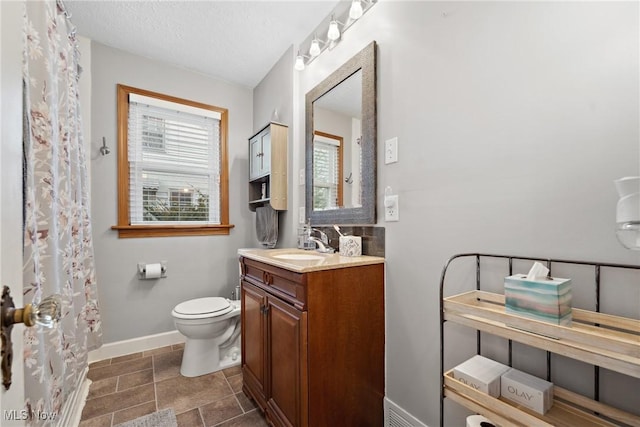 full bath featuring baseboards, toilet, vanity, and a textured ceiling