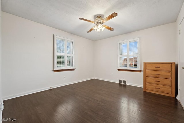 interior space featuring visible vents, a textured ceiling, baseboards, ceiling fan, and dark wood-style flooring