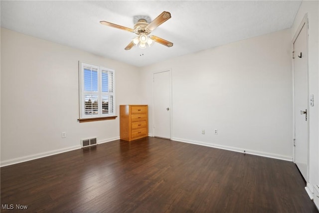 empty room featuring ceiling fan, visible vents, baseboards, and wood finished floors