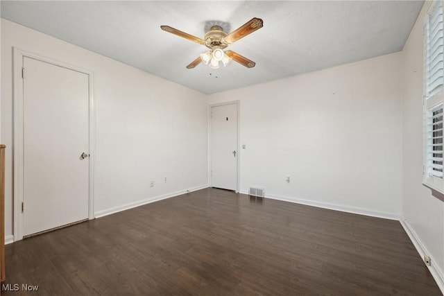 unfurnished bedroom featuring visible vents, baseboards, dark wood-style floors, and a ceiling fan