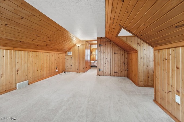 additional living space with visible vents, wooden walls, and vaulted ceiling