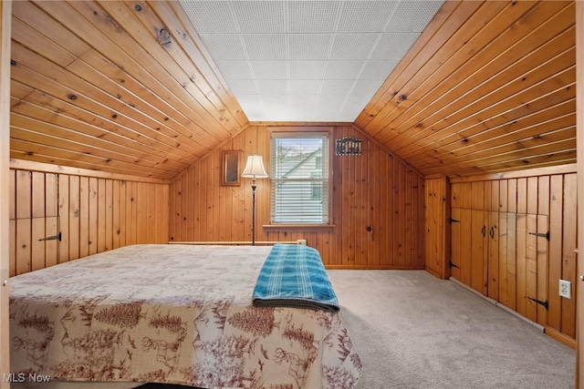 unfurnished bedroom featuring wooden walls, carpet flooring, and lofted ceiling