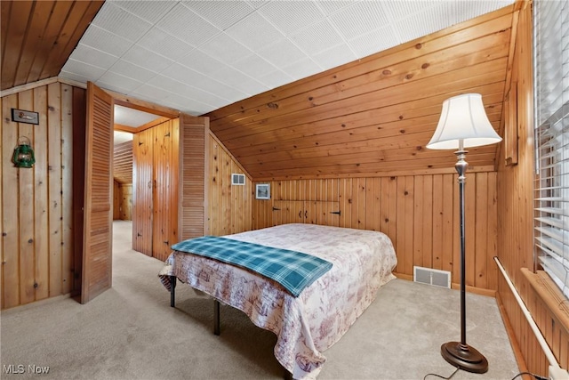 bedroom featuring visible vents, wood walls, carpet flooring, and vaulted ceiling