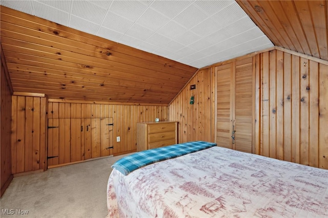 unfurnished bedroom featuring vaulted ceiling, carpet, wood walls, and wooden ceiling