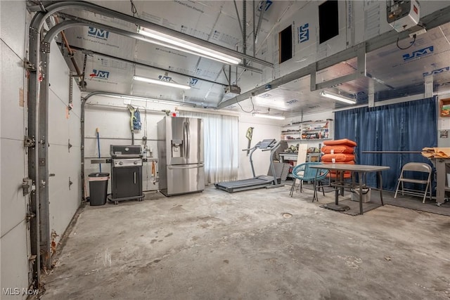 garage featuring stainless steel fridge and a garage door opener