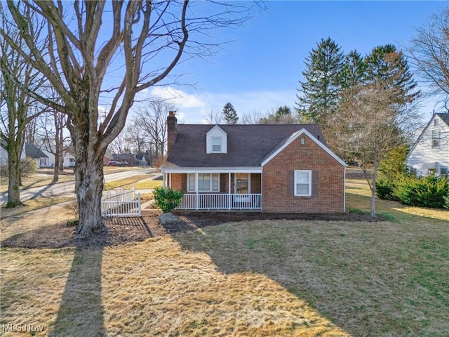 view of front of home with a front yard, brick siding, a porch, and a chimney