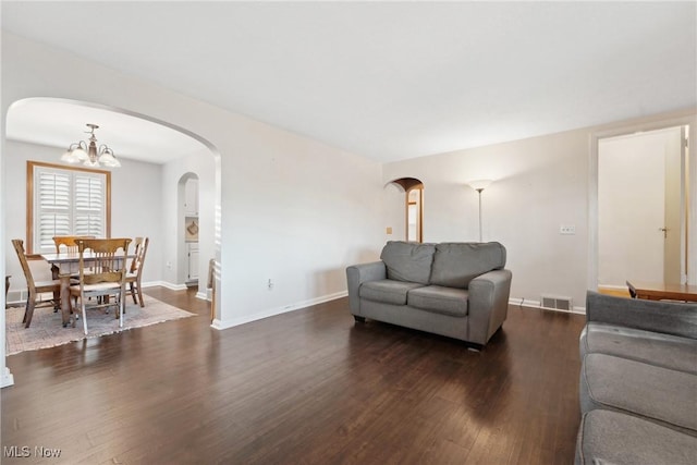 living room with visible vents, arched walkways, an inviting chandelier, and dark wood finished floors