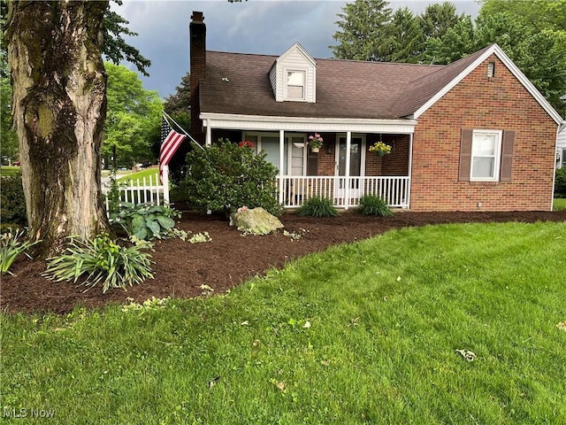 view of front of house with a front lawn, brick siding, covered porch, and a chimney