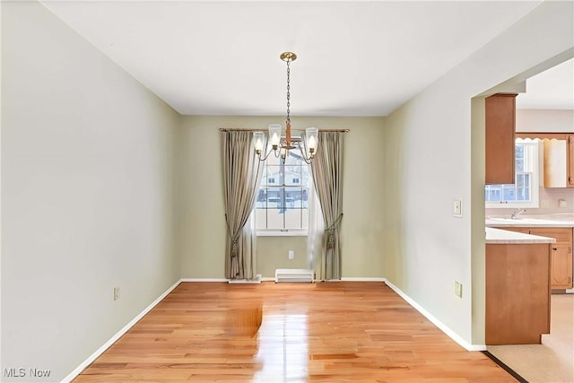 unfurnished dining area featuring baseboards, a baseboard radiator, an inviting chandelier, a sink, and light wood-type flooring