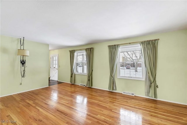 unfurnished living room featuring visible vents, a healthy amount of sunlight, and wood finished floors