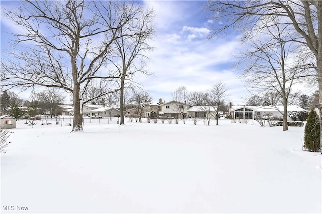 yard layered in snow with fence and a sunroom