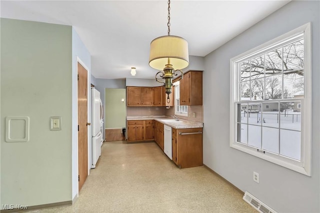 kitchen featuring visible vents, light countertops, brown cabinets, white appliances, and a sink