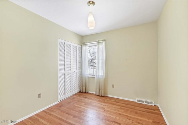 unfurnished bedroom with visible vents, baseboards, a closet, and light wood-style flooring