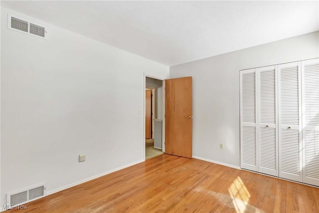 unfurnished bedroom featuring visible vents, baseboards, a closet, and light wood-style flooring