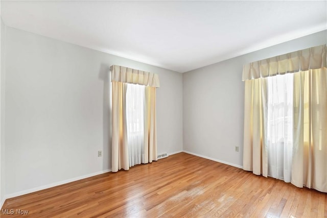 unfurnished room featuring visible vents, baseboards, and light wood finished floors