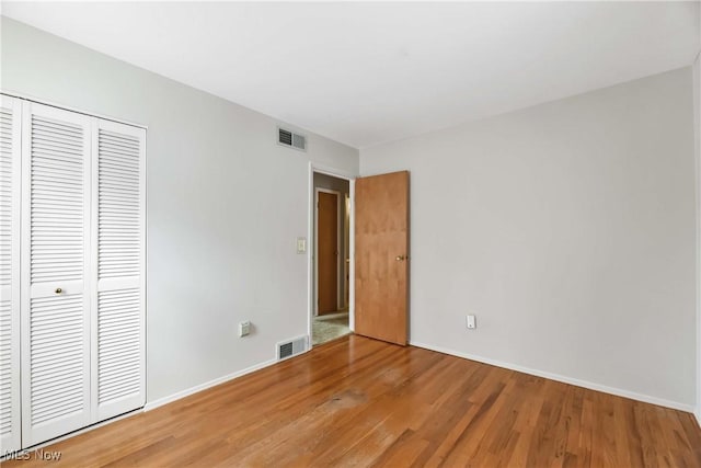 unfurnished bedroom with visible vents, baseboards, a closet, and light wood finished floors