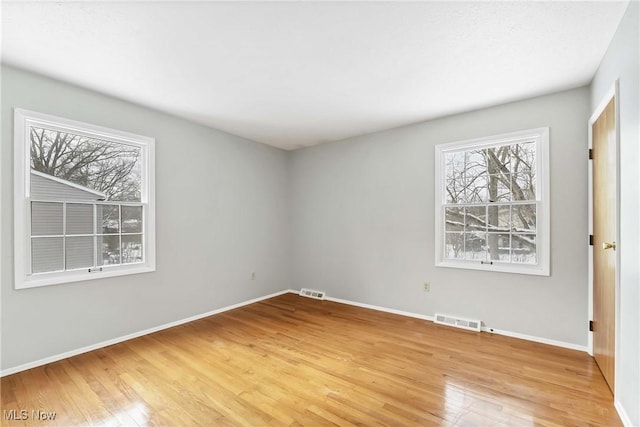 spare room with light wood-style floors, visible vents, and baseboards