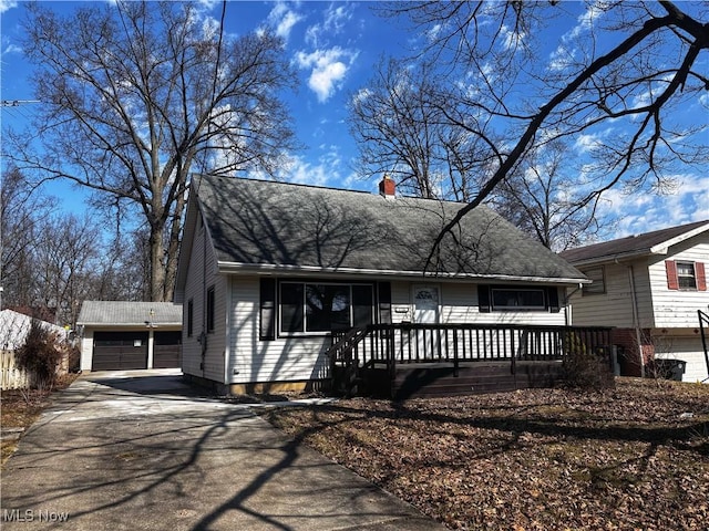 view of front of house with a shingled roof, an outbuilding, a detached garage, and a chimney